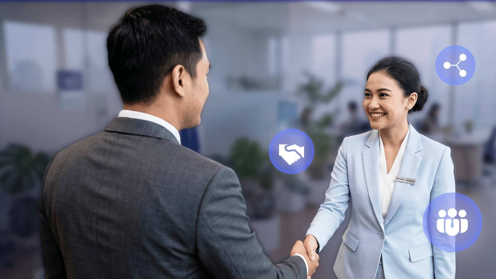 Seorang wanita dan pria berjas saling berjabat tangan di dalam kantor. 